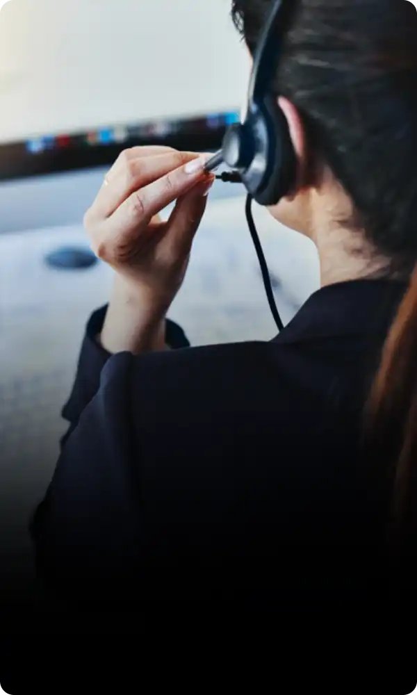 An image showcasing customer support, featuring a woman wearing an overhead headset and working on a computer